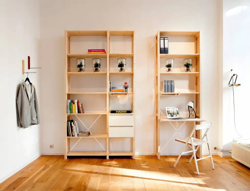 Lichte ruimte met houten vloer, open houten kasten met boeken en planten, minimalistisch bureau met stoel en lamp.