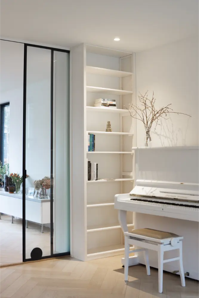 Witte en-suite boekenkast op maat van Lundia in de nis naast de schuifdeur