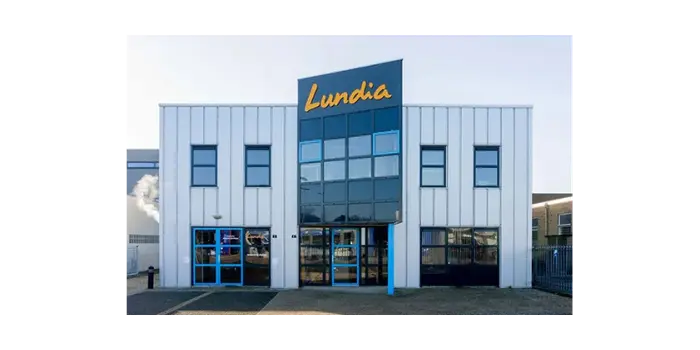 Modern wit bedrijfsgebouw met grote ramen en blauw-geel bord met tekst Lundia boven ingang